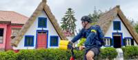 Cyclist passing traditional houses in Santana