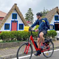 Cyclist passing traditional houses in Santana